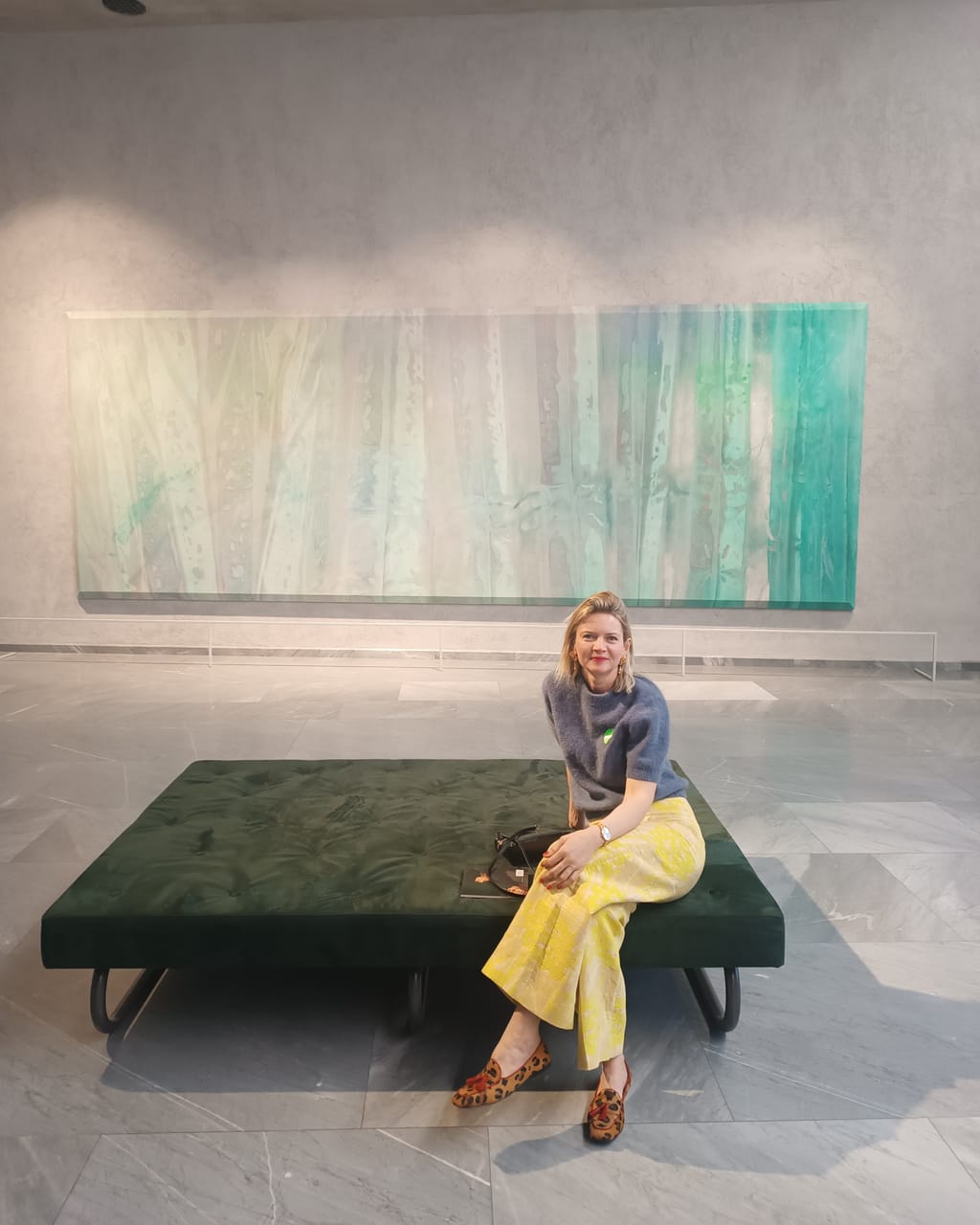 Ella Ens sitzt im Museum vor einem großen grünen Gemälde