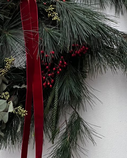 Rote Beeren und das rote Samtband im Kiefernkranz, aus der Nähe