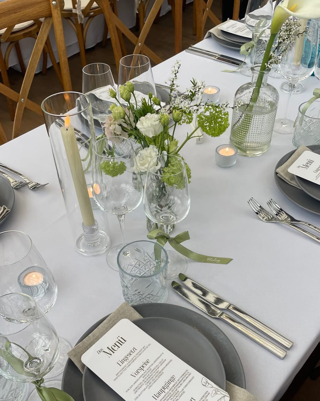 Gedeckte Hochzeitstafel mit kleinen Glasvasen, Kerzen und Menükarte